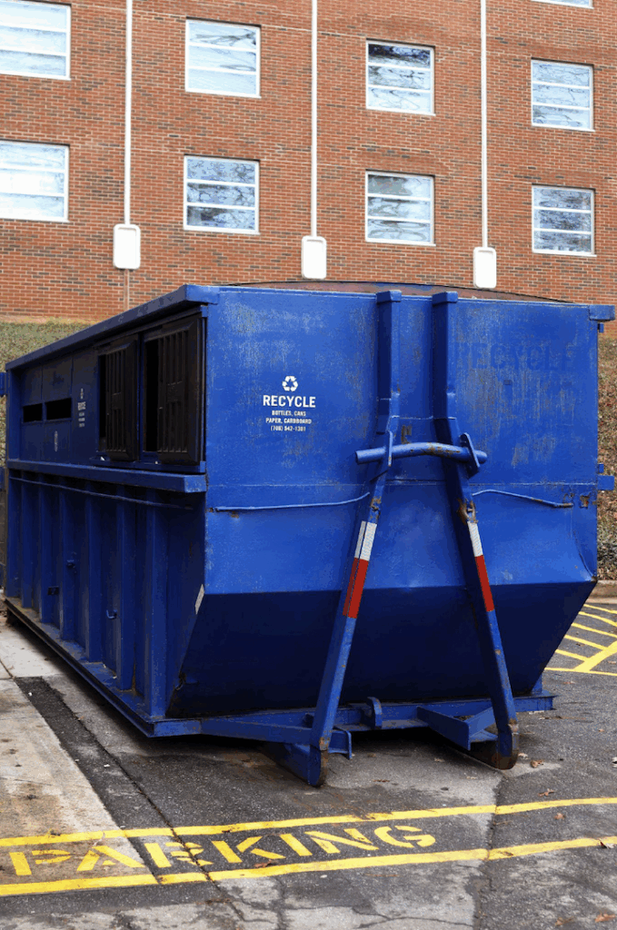 Large blue recycling bin sits outside a building