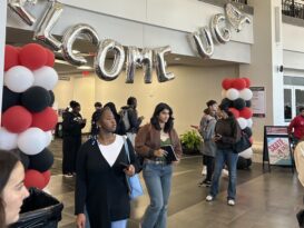 College students walk underneath red, white and black balloons and a welcome to UGA sign on campus