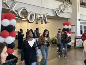 College students walk underneath red, white and black balloons and a welcome to UGA sign on campus