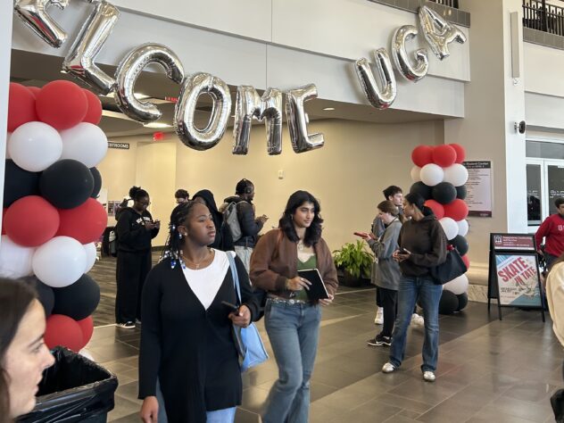 College students walk underneath red, white and black balloons and a welcome to UGA sign on campus