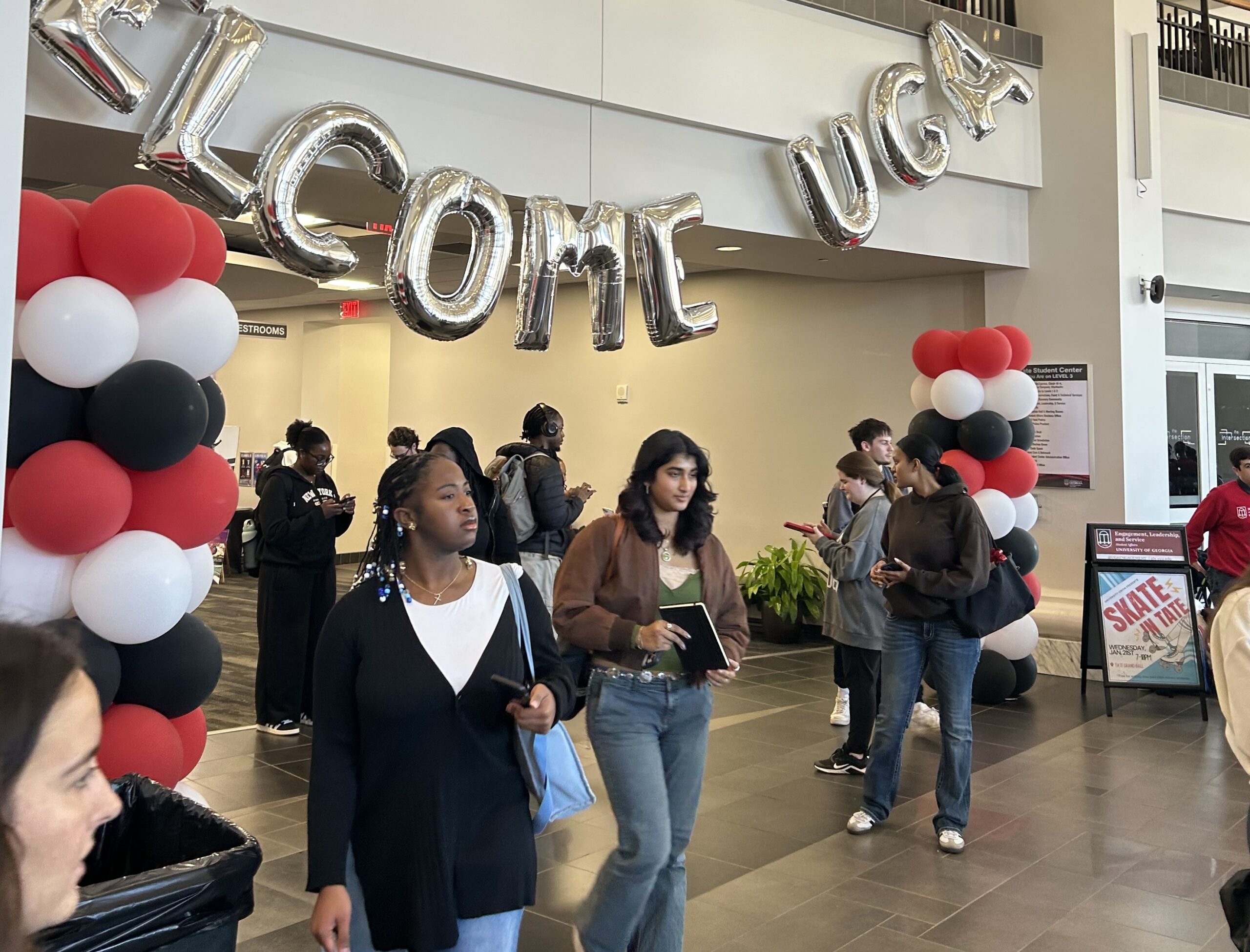 College students walk underneath red, white and black balloons and a welcome to UGA sign on campus
