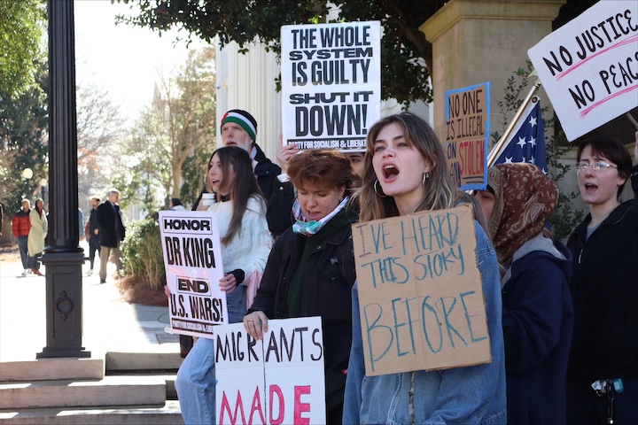 A number of women hold signs and shout during a protest.