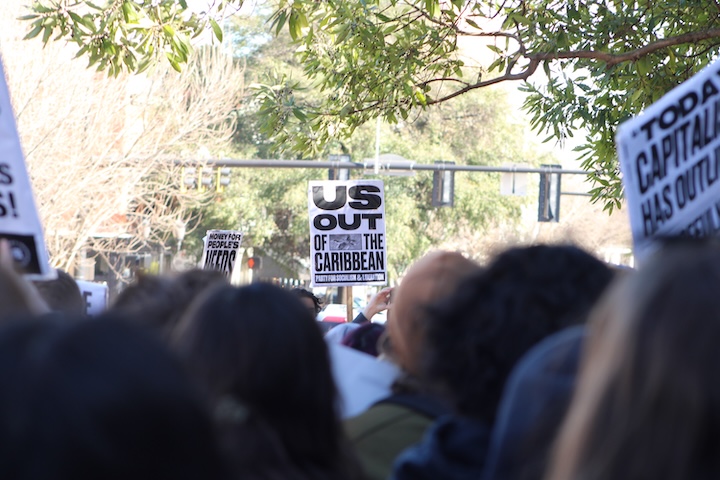 Sign that reads US Out of the Caribbean is held among a group of protestors.