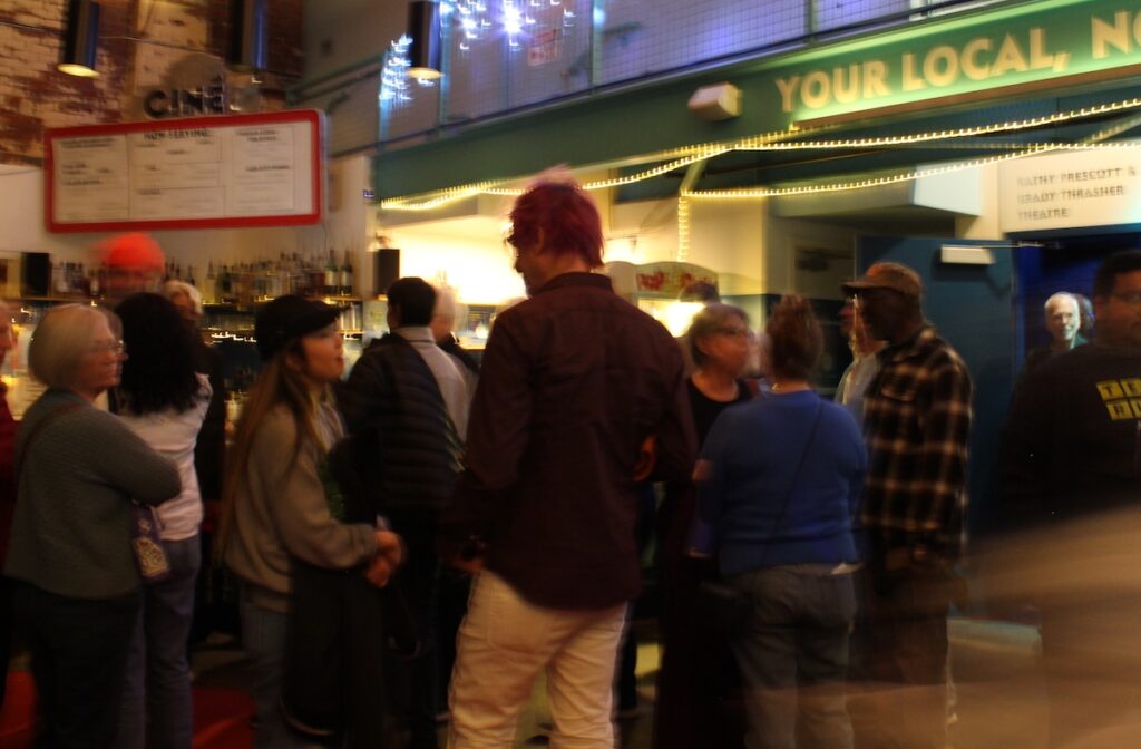 People stand outside talking on a street corner