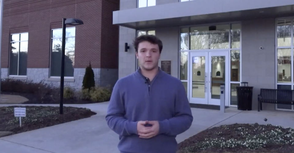 Reporter stands in front of a county municipal building