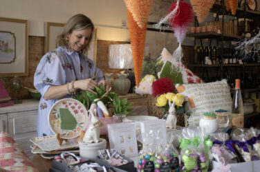 A woman stands next to a store display inside a store.