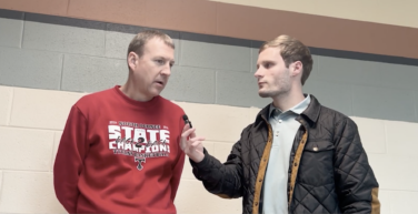 Sports reporter interviewing a coach in a gymnasium