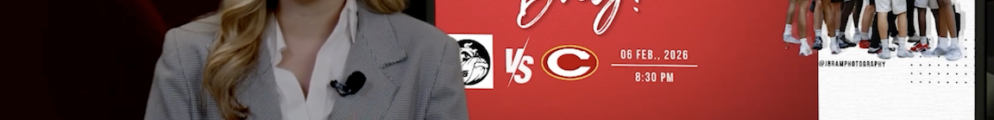 Sports journalist stands in front of a screen with game day logo