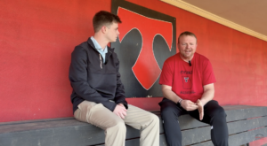 A sports journalist and coach talking in the dugout
