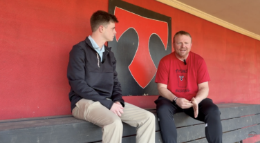 A sports journalist and coach talking in the dugout