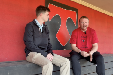 A sports journalist and coach talking in the dugout