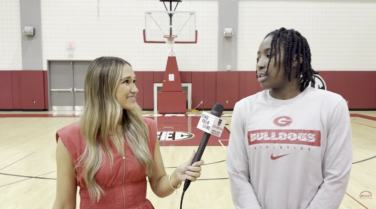 A sports reporter walking and talking with a high school basketball player on the court
