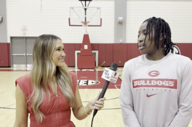 A sports reporter walking and talking with a high school basketball player on the court