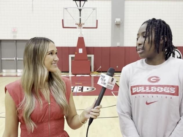 A sports reporter walking and talking with a high school basketball player on the court