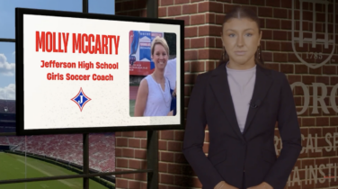 Sports reporter stands next to a screen with information on it
