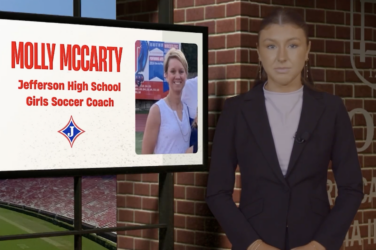 Sports reporter stands next to a screen with information on it