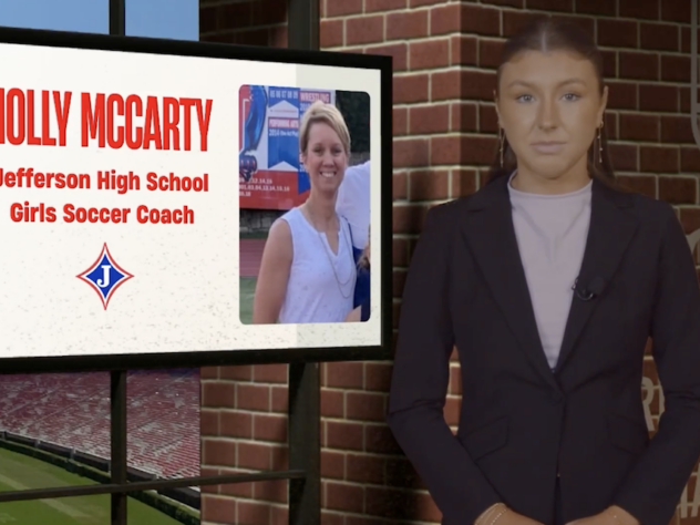 Sports reporter stands next to a screen with information on it