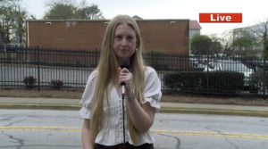 A reporter stands outside a building.