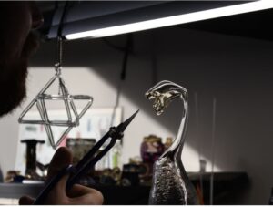 Glass sculpture seen with hand holding tool
