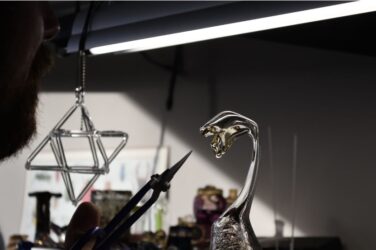 Glass sculpture seen with hand holding tool