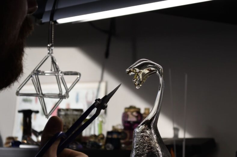 Glass sculpture seen with hand holding tool