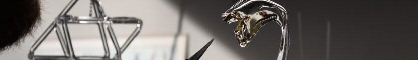 Glass sculpture seen with hand holding tool