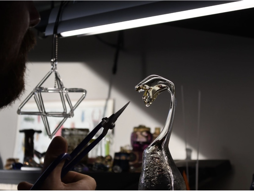 Glass sculpture seen with hand holding tool