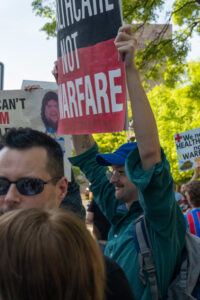 A man in a green shirt holds a black and red sign