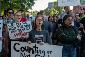 A crowd of protesters holding signs chant