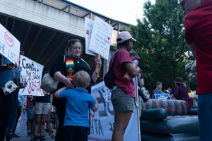 A woman hugs a child while holding a protest sign.