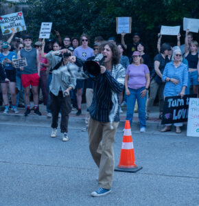 Aspen David yells into a megaphone in front of a group of protesters