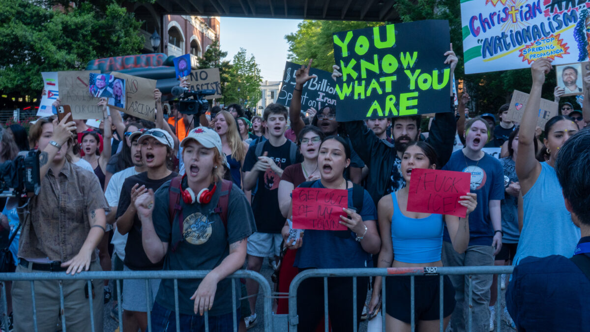 A line of protesters yell towards the Arena