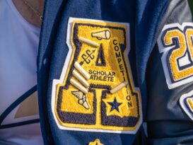 A high school letter jacketed decorated with numerous symbols, including stars.