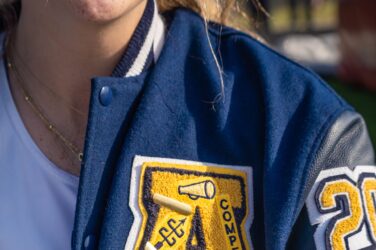 A high school letter jacketed decorated with numerous symbols, including stars.