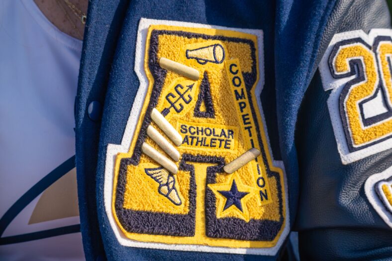 A high school letter jacketed decorated with numerous symbols, including stars.