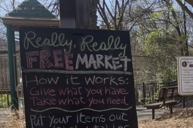 A sign reads: Really, Really Free Market. How it Works: Give what you have. Take what you need. Put your items out on Labeled tables. Please dirty, stained or torn items. Please observe the 'CLAIMED" area, items in this area are already claimed THIS IS A NO-MONEY MARKET. NO TRADE, SWAP, BARTER OR SALE