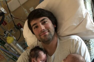 A father holding tiny baby boys.