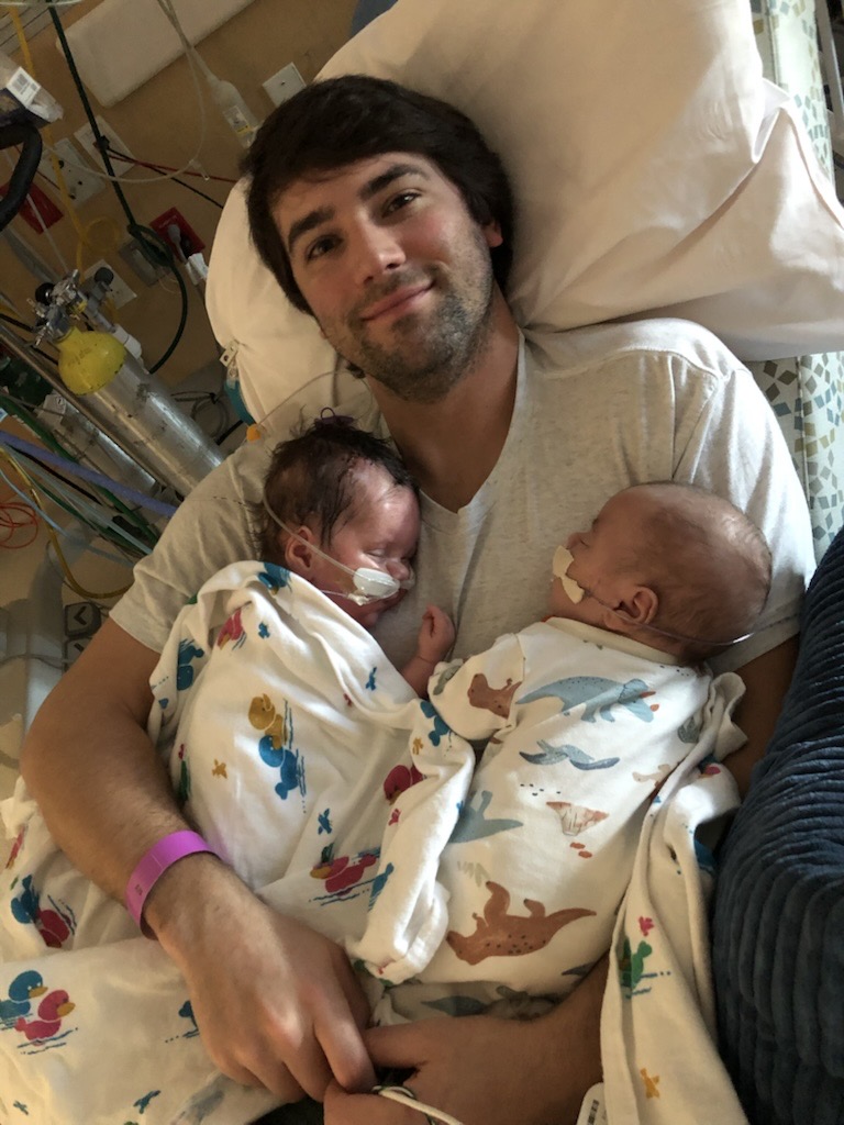 A father holding tiny baby boys.