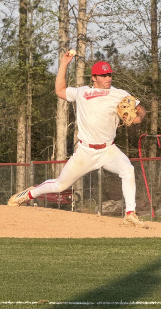 A high school pitcher takes a long stride in his windup.