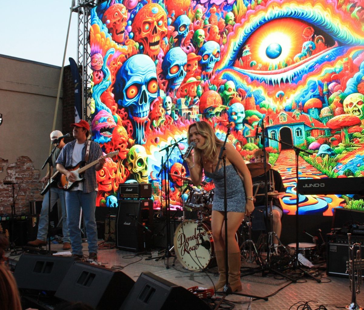 Sweet Tea Pedigree singers Amelia Duffner and Wyatt Baugh sing into microphones on the Paloma Park stage.
