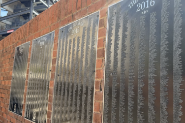 Senior Signature plaques displaying hundreds of engraved names hang on a brick wall at the Tate Student Center Plaza at the University of Georgia.