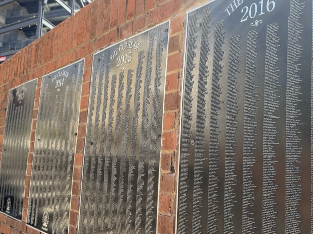 Senior Signature plaques displaying hundreds of engraved names hang on a brick wall at the Tate Student Center Plaza at the University of Georgia.