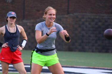 A flag football coach watches a quarterback prepare to catch the ball.