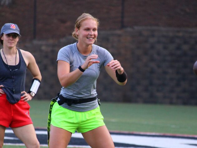 A flag football coach watches a quarterback prepare to catch the ball.