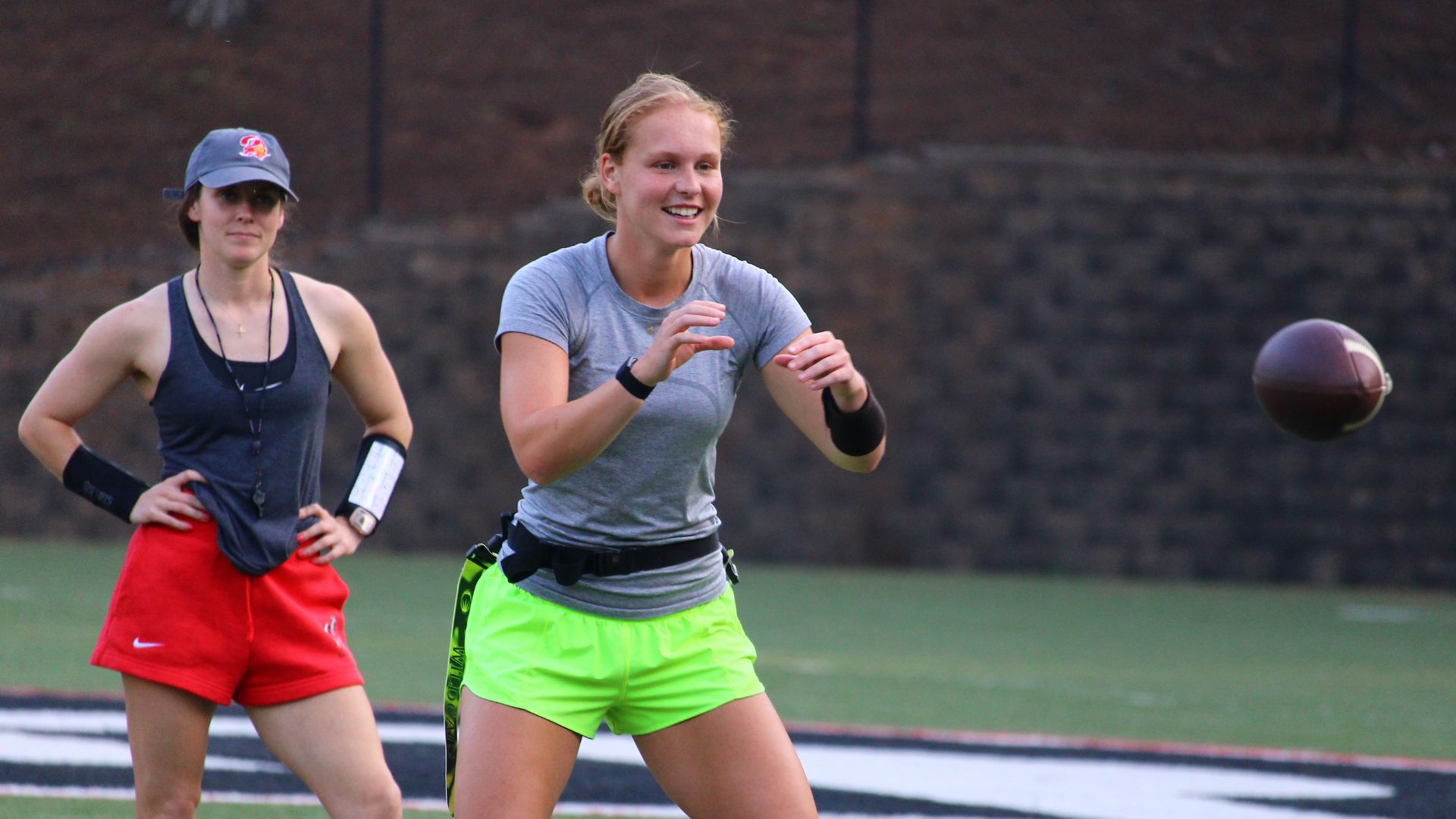 A flag football coach watches a quarterback prepare to catch the ball.