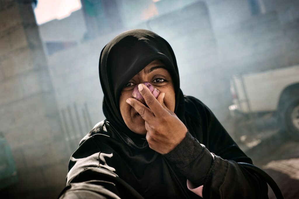 Bahrain, 2011 a woman holds a cloth over her face to shield from tear gas