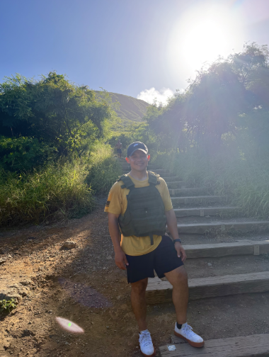 Man with weighted vest stands on the stairs of a mountain climb