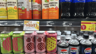 Rows of soda cans sit on a shelf with English and Japanese labeling