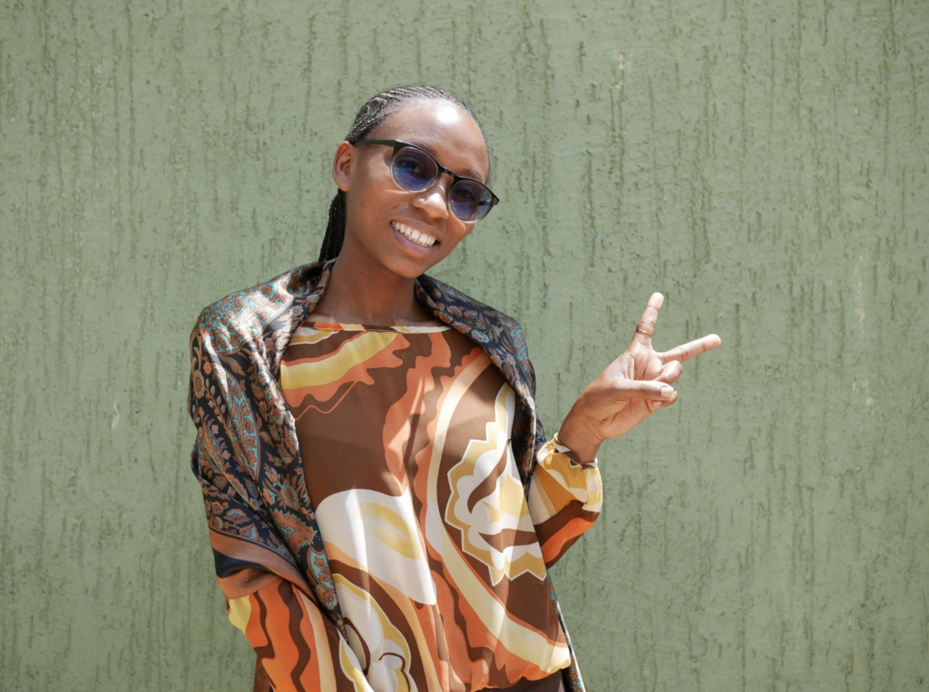 A woman smiles at the camera and holds up a peace sign with her fingers