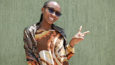 A woman smiles at the camera and holds up a peace sign with her fingers